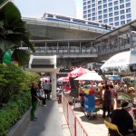 Songkran auf der Silom Road - Schaulustige beobachten das Treiben aus sicherer Entfernung im Zugang zur Skytrain Station.
